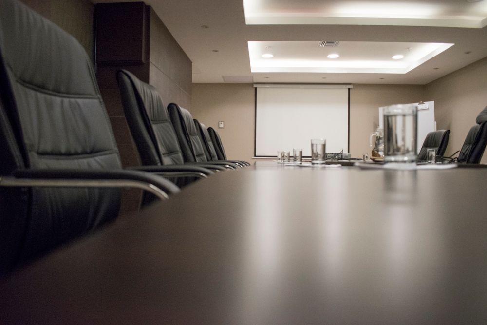 A conference room with a polished wood table and leather chairs, empty and set for the morning.