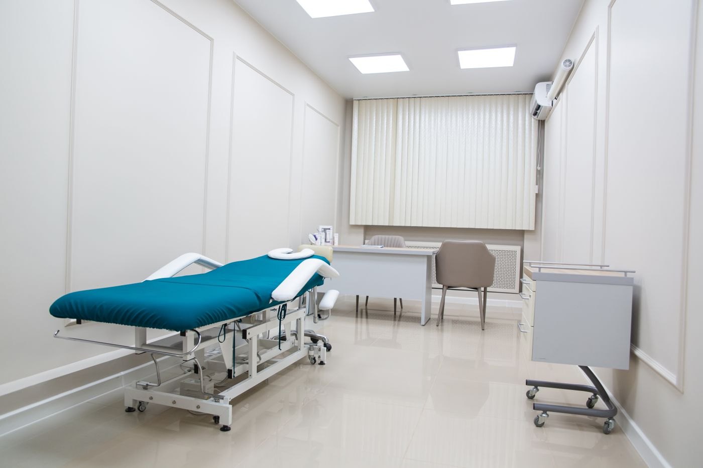 An empty therapy treatment room with the table made up, a face cradle fitted, and a clinician's desk beyond it.